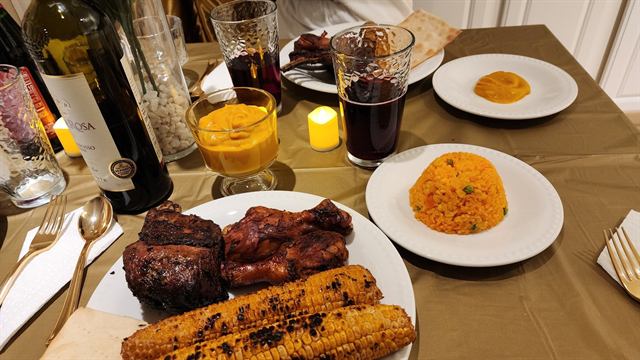 Dinner spread with grilled meat, charred corn, and seasoned rice