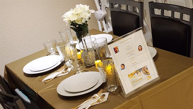 Intimate dinner table with candles, white flowers, and a printed menu