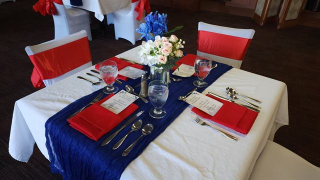 Table set in red, white, and blue with folded red napkins and fresh flowers