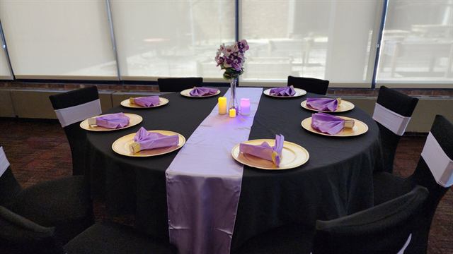 Black tablecloth with a lavender runner, gold chargers, and purple napkins