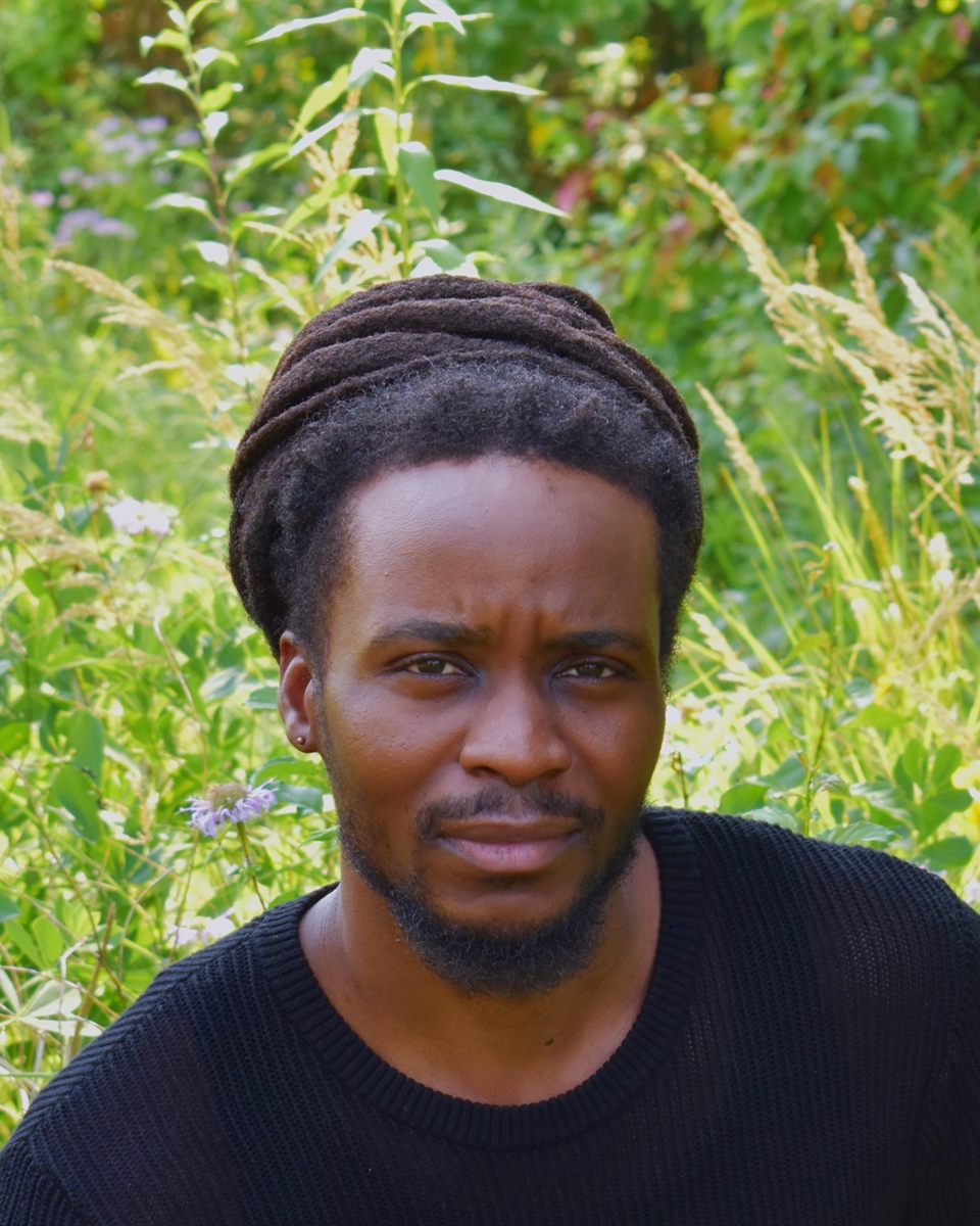 Marx Mumbuwa, founder of Gorilla Nest Fitness, outdoors among tall grasses and wildflowers